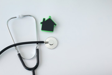 green home with stethoscope on white background