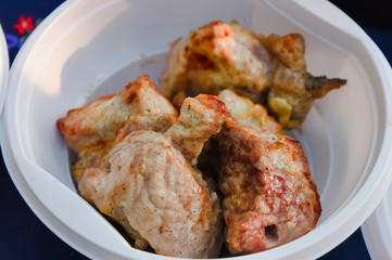 Serving of barbecue in a white disposable plate close-up.