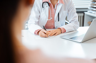 Close-up of doctor taking notes while having appointment with patient