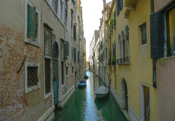 Fototapeta na wymiar Canal entre casas en Venecia con botes un dia soleado