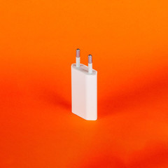 White USB euro plug wall charger adapter for mobile phone on orange background