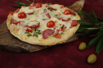 Pepperoni Pizza with Mozzarella cheese, sausages salami, Spices, tomato, olive and branch of olive for decoration. Italian pizza isolated on red background. Food background. 
