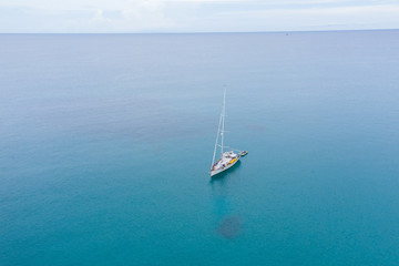 Fototapeta premium Aerial view of white Yacht in deep blue sea with beautiful landscape view in Kudat, Sabah, Borneo