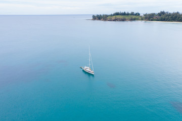 Fototapeta premium Aerial view of white Yacht in deep blue sea with beautiful landscape view in Kudat, Sabah, Borneo