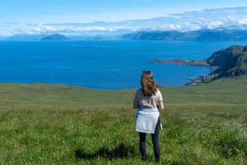 Fototapeta na wymiar Girl looking at the beautiful scenery from the islands of Runde in Norway during summer holiday. Vacation, sunny, blue sky, girl, hiking concept.