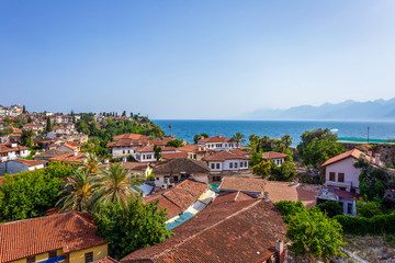 Fototapeta na wymiar Beautiful aerial view of old red roofs of many small houses, peaceful blue sea water and foggy mountains. Antalya city, Turkey country. Horizontal color photography.