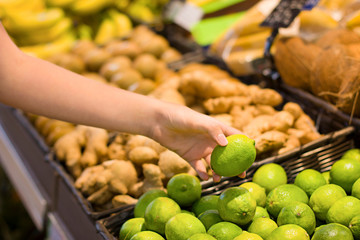 Female hand choosing lemon in the market.  Concept of information eating products, organic fruit and vegetables. 