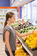 Teen girl shopping in supermarket, reading product information. Choosing daily product. Concept of healthy food, bio, vegetarian, diet.