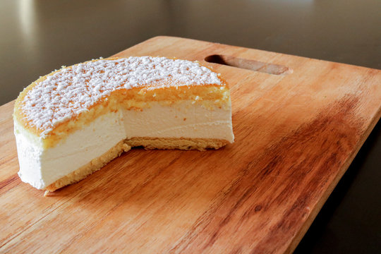 Primo piano di una soffice torta alla ricotta su un tagliere di legno, ricette e dessert