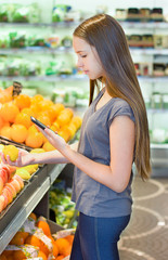 Teen girl shopping in supermarket, reading product information. Choosing daily product. Concept of healthy food, bio, vegetarian, diet.