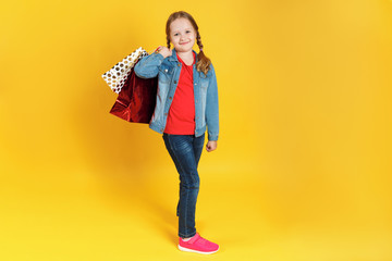Little girl with bags on a yellow background