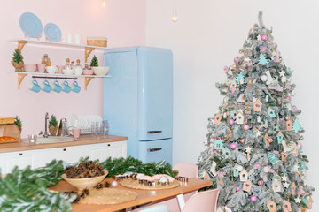 Pink and blue pastel modern kitchen interior decorated with Christmas tree and decorative elements. New Year decorations, Happy Winter Holidays. Kitchen accessories, dishes and hanging blue cups.