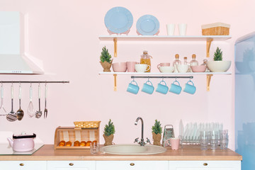 Pink and blue pastel modern kitchen interior. Kitchen accessories, containers with cereals, dishes and hanging blue cups.