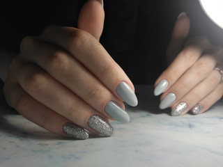 Glossy light grey gel Polish with glitter design. Grey coating on long nails with silver design....