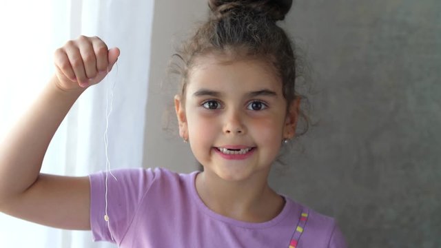 Portrait of a smiling toothless child holding a tooth on a string. Successful attempt to remove a tooth. Pull out the tooth with a thread. Remove the tooth at home.