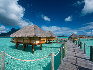BORA BORA, FRENCH POLYNESIA - SEPTEMBER 5, 2018 - Luxury overwater villas on blue lagoon, white sandy beach and Otemanu mountain at Bora Bora island, Tahiti, French Polynesia