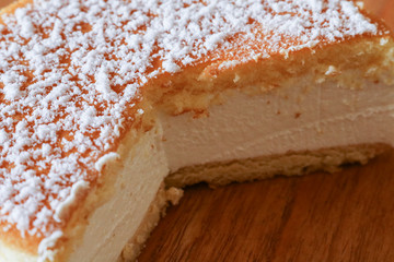 Primo piano di una soffice torta alla ricotta su un tagliere di legno, ricette e dessert