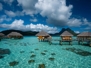 Luxury overwater villas on blue lagoon, white sandy beach and Otemanu mountain at Bora Bora island, Tahiti, French Polynesia.