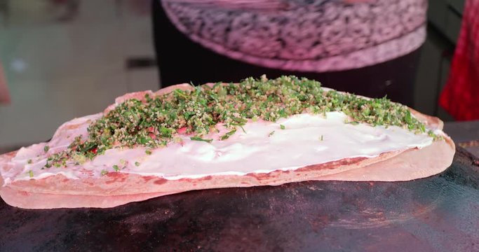 Druze Mediterranean Pita bread on hot plate (Taboon). Druze woman hands baking a traditional Druze Pita with cheese and TABULE salad.