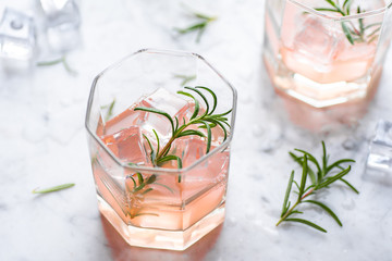 Pink grapefruit and rosemary drink, backlight on white background