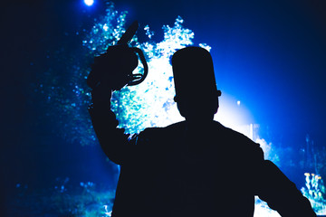Man in mask with chainsaw posing over dark background