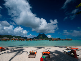 BORA BORA, FRENCH POLYNESIA - SEPTEMBER 5, 2018 - Luxury overwater villas on blue lagoon, white sandy beach and Otemanu mountain at Bora Bora island, Tahiti, French Polynesia.