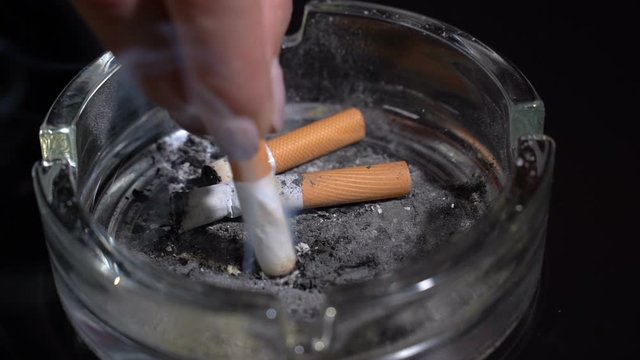 Hand extinguish a cigarette in an ashtray close-up.Slow motion
