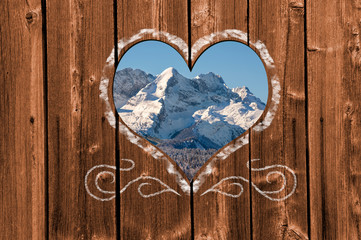 View to the Zugspitze through a carved heart at wooden wall