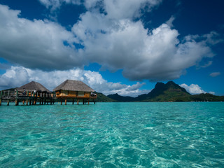 Luxury overwater villas on blue lagoon, white sandy beach and Otemanu mountain at Bora Bora island, Tahiti, French Polynesia.