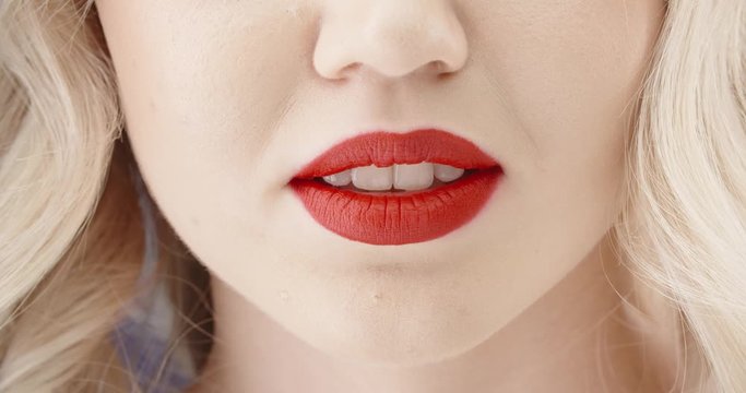 Close up shot of girl wearing makeup with red lipstick and perfect teeth doing a seductive growl - emotions concept 4k footage