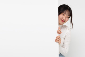 Smiling happy Asian woman standing behind big white poster isolated on white background