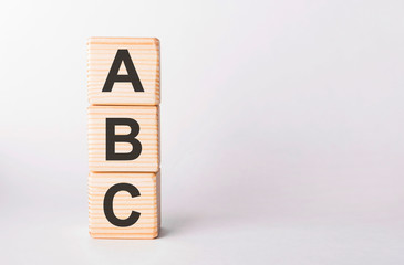 ABC letters of wooden blocks in pillar form on white background, copy space