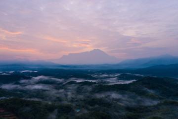Aerial drone image of Beautiful harmony romantic color sunrise landscape scenery with sunlight and fog and Mount Kinabalu as background in Guakon, Sabah, Malaysia