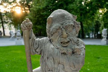 Fototapeta na wymiar One of the creepy statues of the Dwarf Garden, near Mirabell Garden, at sunset.