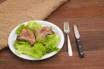 Roasted lamb chop served in a plate with lettuce