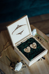 Two golden wedding rings in decorative wooden box on green leaves