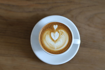Cup of cappuccino with latte art on wooden background. Latte Coffee art on the wooden table. cup of coffee on table in coffee shop cafe