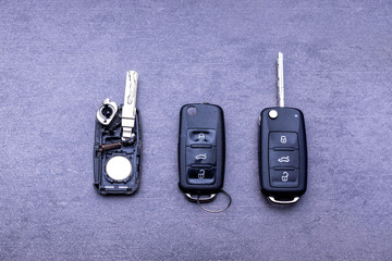 Broken or damaged remote key fob and new vehicle key on gray background. Broken or damaged remote key fob of any vehicle car service.- Image