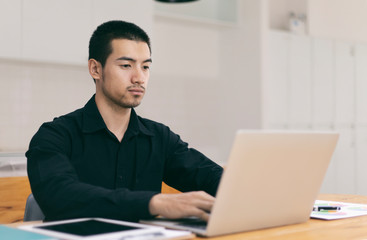 Portrait of a young business man using laptop computer while working. Young asian business men working with laptop in coffee shop cafe.