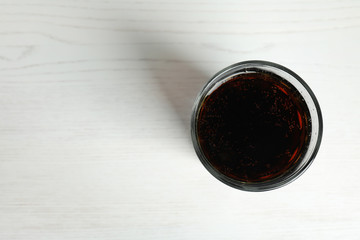 Glass of refreshing soda drink on white wooden background, top view. Space for text