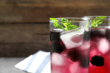 Delicious refreshing blackberry lemonade against wooden background, closeup. Space for text