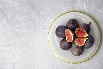 Plate with ripe figs on light grey marble table, top view. Space for text