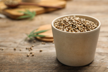 Organic hemp seeds in bowl on wooden table