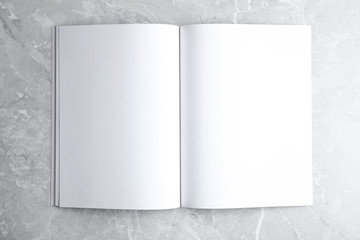 Blank open book on light grey marble background, top view. Mock up for design