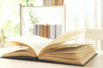 Open hardcover book on white wooden table indoors