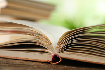 Open hardcover book on wooden table against blurred background, closeup