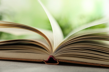 Open hardcover book on table against blurred background, closeup