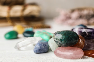 Pile of different gemstones on white wooden table. Space for text