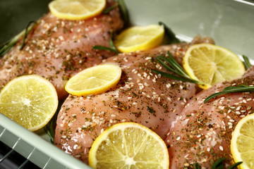 Chicken breasts with lemon and rosemary in baking dish, closeup