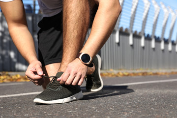 Fototapeta premium Sporty man tying shoelaces before running at stadium